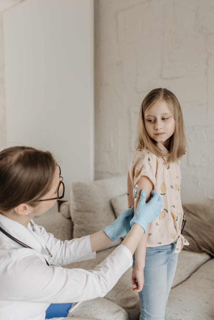A doctor in glasses vaccinates a child in a cozy room, emphasizing healthcare.